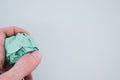 Hand holding a green crumpled paper ball on a light green background Royalty Free Stock Photo