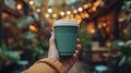 a hand holding a green disposable coffee cup in a cafeteria