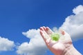 Hand holding green globe with eco energy icon on blue sky Royalty Free Stock Photo