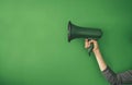 Hand Holding Green Megaphone Against Solid Green Background in Minimalist Style Creating a Bold Statement Royalty Free Stock Photo