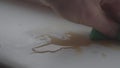 Hand holding green sponge sponging off spilled coffee on white wooden table or windowsill
