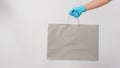 Hand holding grey shopping bag and wear blue medical glove isolated on white background