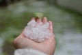 HAND HOLDING HAILSTONE AFTER A HAILSTORM IN A FIEL. DEFOCUSED BA Royalty Free Stock Photo