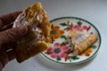 Hand holding half of a broken apple hand-pie turnover above a plate