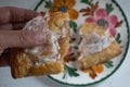 Hand holding half of a broken apple hand-pie turnover above a plate