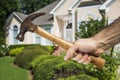 Hand Holding Hammer in front of House