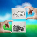 Hand holding hand drawn house and car