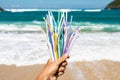 Hand holding heap of plastic straws on ocean beach Royalty Free Stock Photo