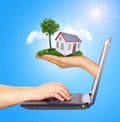 Hand holding house on green grass with tree, solar Royalty Free Stock Photo