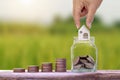 Hand holding house model in a jar for saving money and stacks of coins on a wooden floor, financial concept. Royalty Free Stock Photo