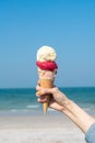 Hand holding ice cream cone with blue sky background Royalty Free Stock Photo