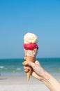 Hand holding ice cream cone with blue sky background Royalty Free Stock Photo