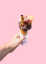 Hand Holding Ice Cream Cone In Front Of Pink Background