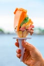 Hand holding ice cream cone with several layers of different colHand holding ice cream cone with several layers of different color