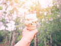 Hand holding ice cream over blurred green forest background Royalty Free Stock Photo