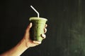 Hand holding Iced Green matcha tea mixed with ice cube and milk in latte glass dark background Royalty Free Stock Photo