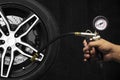 Hand holding an inflator gauge tools, Alloy wheel of racing car