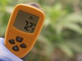 Hand Holding Infrared Thermometer Over Green Foliage Royalty Free Stock Photo