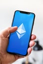 Hand holding iphone smartphone with ETH Ethereum crypto currency logo, Paris, France