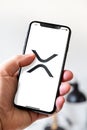 Hand holding iphone smartphone with XRP Ripple crypto currency logo, Paris, France