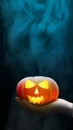 Hand holding Jack-o-Lantern with a dark smoke background