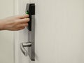 Hand holding key card in front of electronic lock to open white door room in hotel Royalty Free Stock Photo