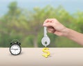 Hand holding key with dollar sign keyring and alarm clock Royalty Free Stock Photo