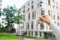 Hand holding keys on the background of a new building, construction concept. Buying real estate, housing, apartments Royalty Free Stock Photo