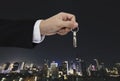 Hand holding keys with city background, real estate and property concept Royalty Free Stock Photo