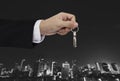 Hand holding keys with city background, real estate and property concept Royalty Free Stock Photo