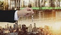 Hand holding keys, with site construction and city in sunset background Royalty Free Stock Photo