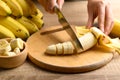 Hand holding kitchen knife and cutting ripe banana fruit Royalty Free Stock Photo