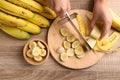 Hand holding kitchen knife and cutting ripe banana fruit Royalty Free Stock Photo