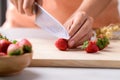 Hand holding kitchen knife and cutting strawberry