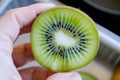 hand holding a kiwi sliced in half, seeds visible