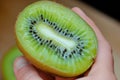 hand holding a kiwi sliced in half, seeds visible