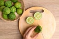 Hand holding knife and cutting kaffir lime on wooden Royalty Free Stock Photo