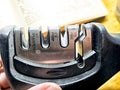 Knife sharpener tool being held for use on a wooden surface in a well-lit kitchen setting Royalty Free Stock Photo