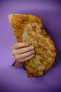 Hand holding large fried empanada against purple background Royalty Free Stock Photo