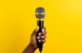 hand holding large microphone on yellow background Royalty Free Stock Photo