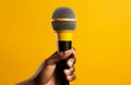 hand holding large microphone on yellow background Royalty Free Stock Photo