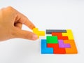 Hand holding the last piece to complete a square tangram puzzle colorful wooden puzzle for kid on white background Royalty Free Stock Photo