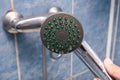 Hand holding leaking, dropping dirty calcified shower head, clogged nozzles, injectors with limescale