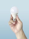 Hand holding a LED light bulb on blue background. Using economical and environmentally friendly light bulb concept. Idea. Energy