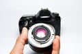 Hand holding lens DSLR camera isolated on pink background