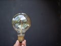 A hand is holding a light bulb against a dark background. The lightbulb represents idea and innovation concept Royalty Free Stock Photo