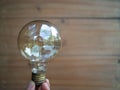 A hand is holding a light bulb against a dark background. The lightbulb represents idea and innovation concept Royalty Free Stock Photo