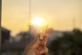 Hand holding light bulb against nature on green leaf with energy sources for renewable Royalty Free Stock Photo