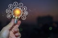 Hand holding light bulb against nature with icons energy sources for renewable Royalty Free Stock Photo