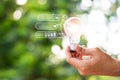 Hand holding light bulb against nature with icons green energy sources for renewable . Plant growing in the bulb concept Royalty Free Stock Photo